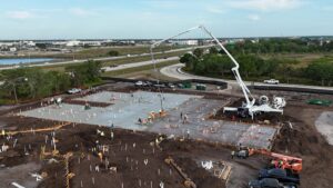 Daytime commercial slab-on-grade pour with anchor bolts set in the deck